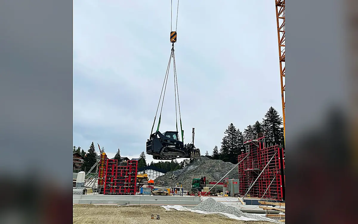 Der Raupenlader wird in Crans-Montana per Kran auf die Baustelle gehoben